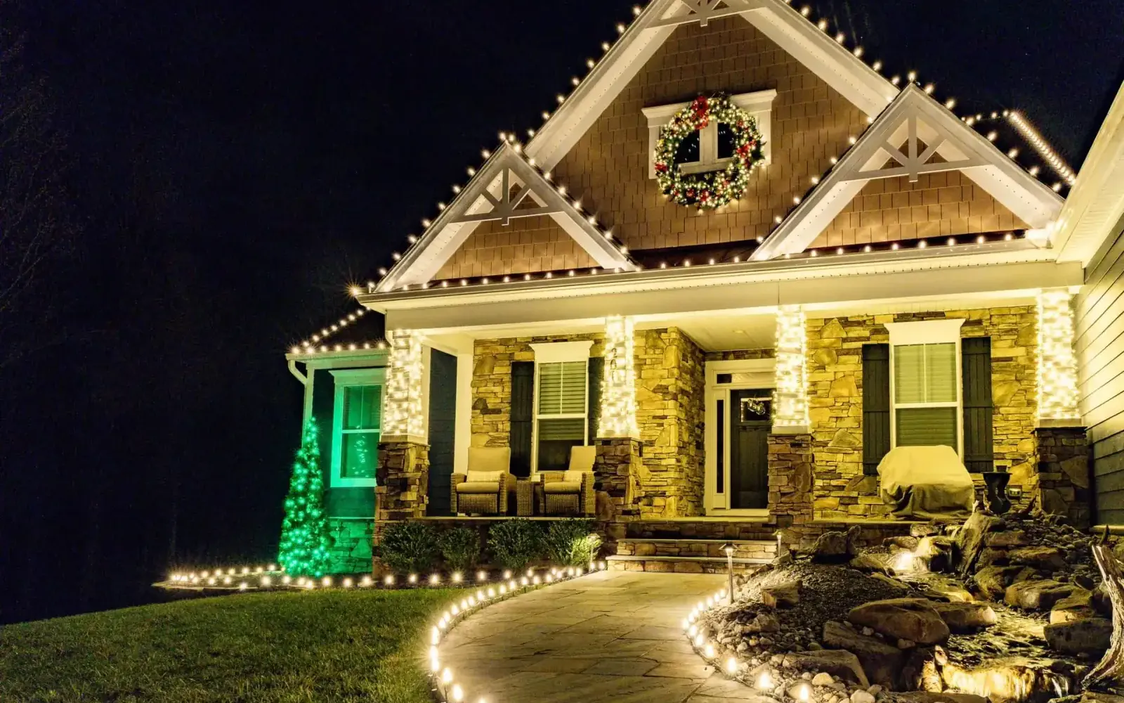 Warm white Christmas lights along a home's roofline, porch columns, and front walkway